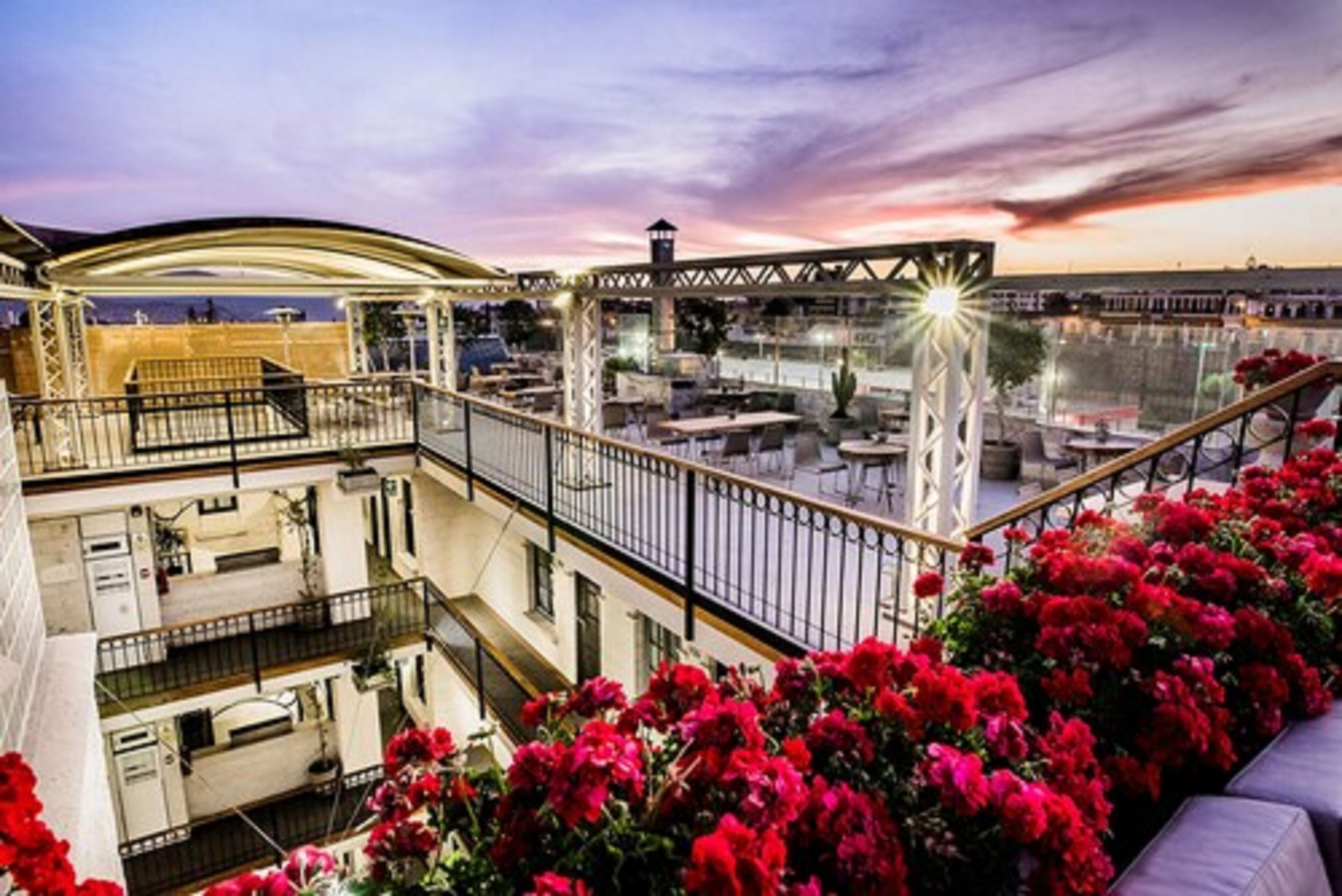 A rooftop terrace with a view of the city, featuring a covered seating area and a railing.