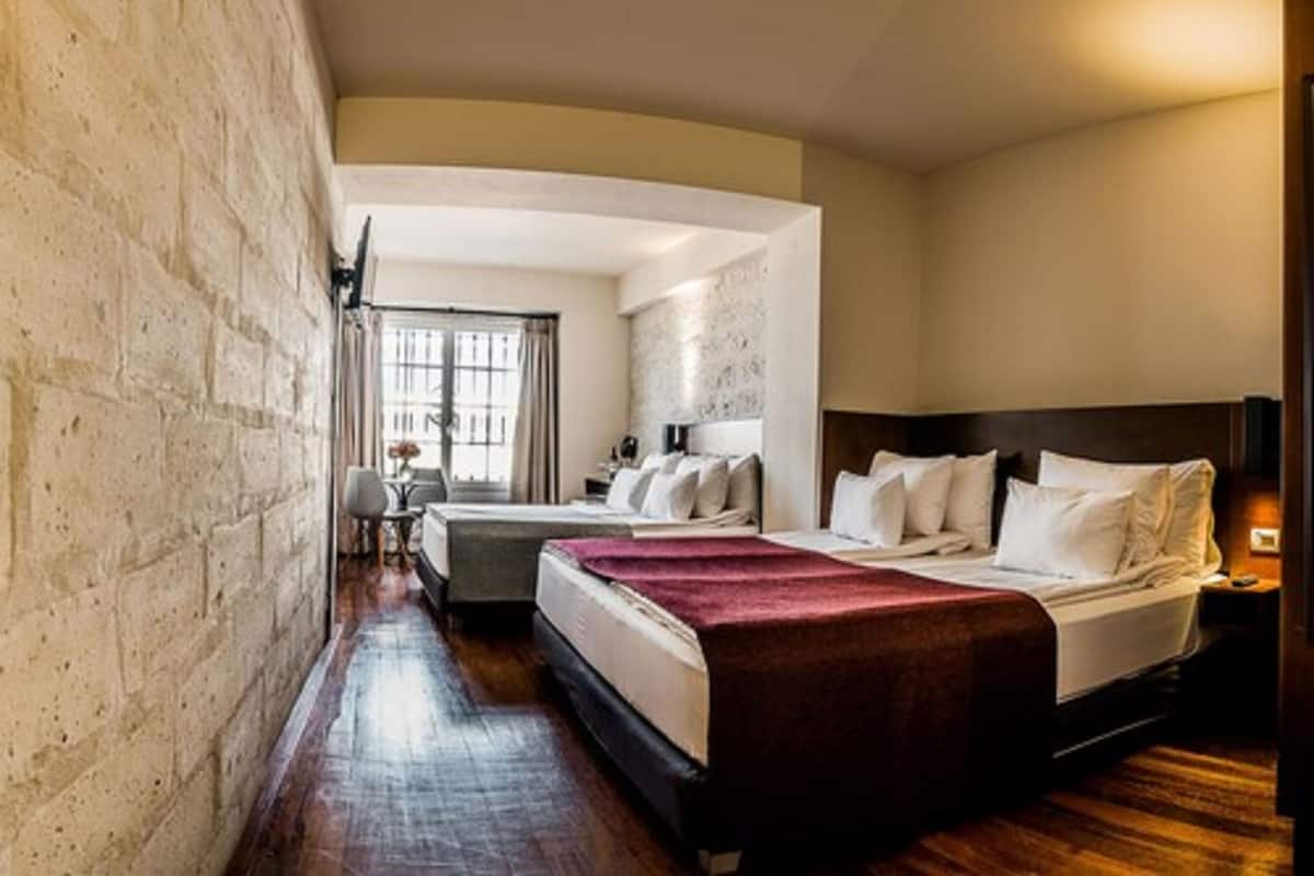 A hotel room with two beds, a desk, and a chair.