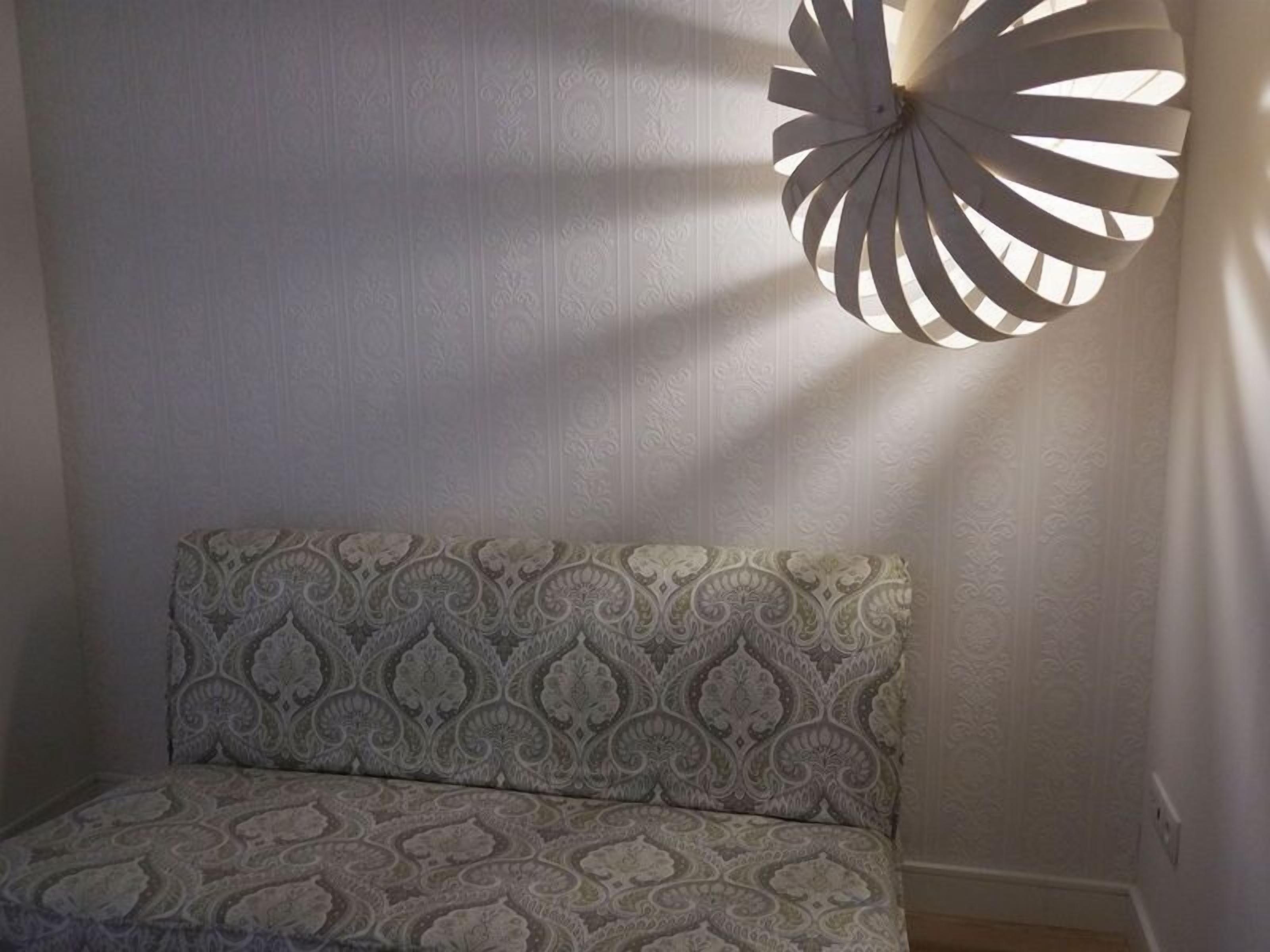 A patterned sofa against a wall with a decorative light fixture.