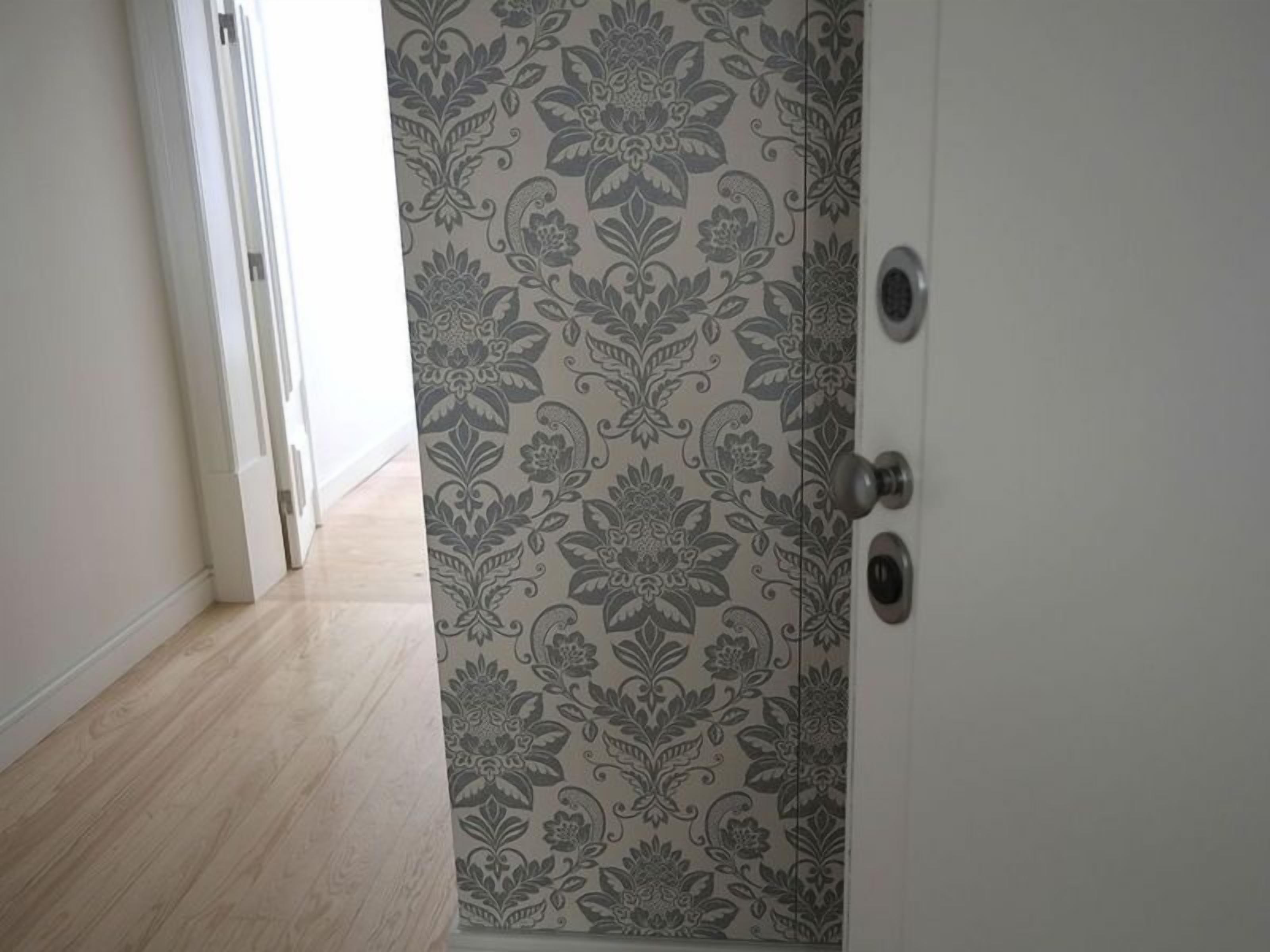 Eine Tür mit floralem Muster, ein heller Holzboden und eine weiße Wand.