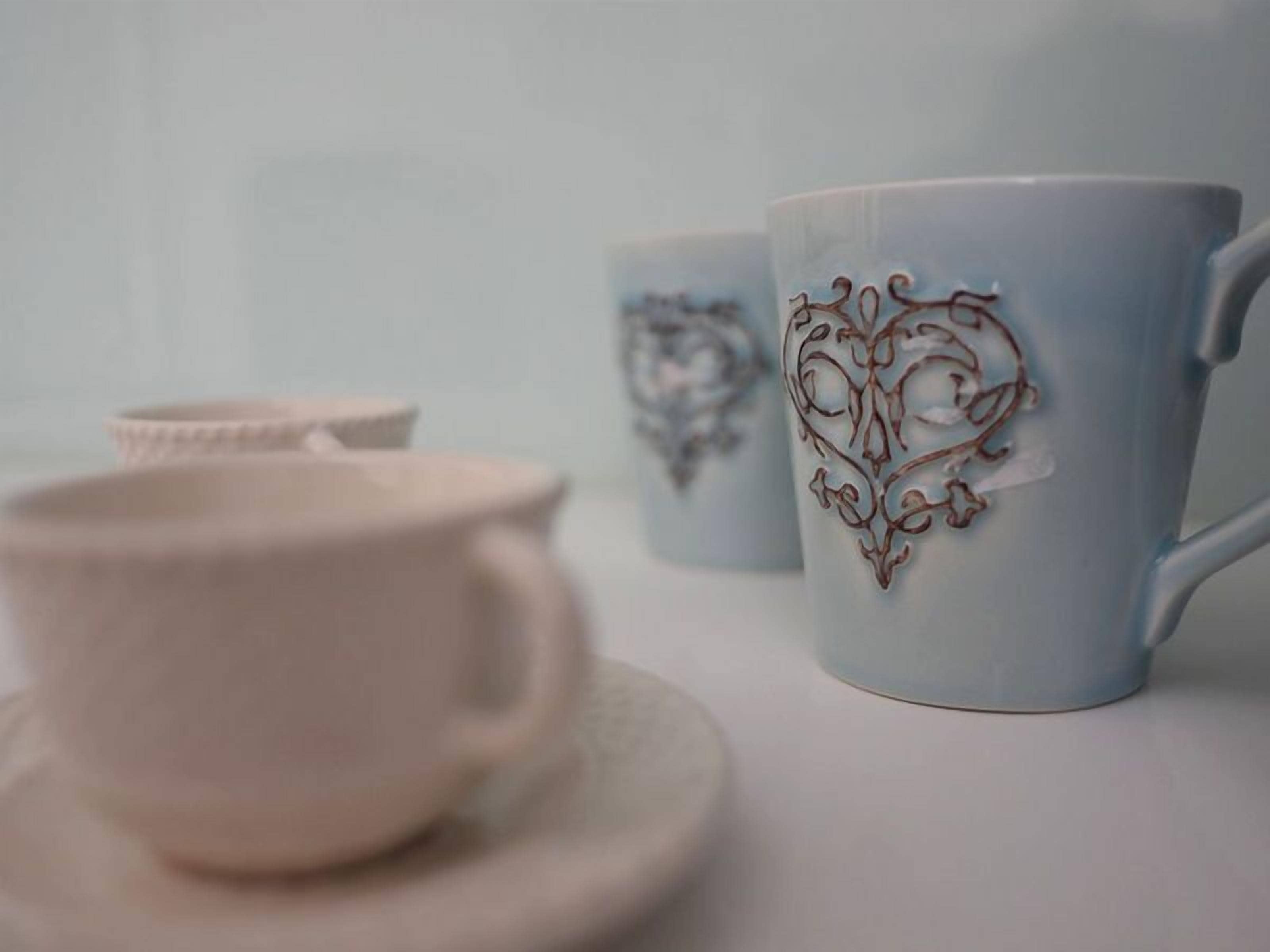 Un ensemble de tasses et de soucoupes en céramique blanche ornées de motifs complexes en forme de cœur.