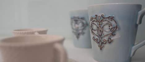 Un ensemble de tasses et de soucoupes en céramique blanche ornées de motifs complexes en forme de cœur.