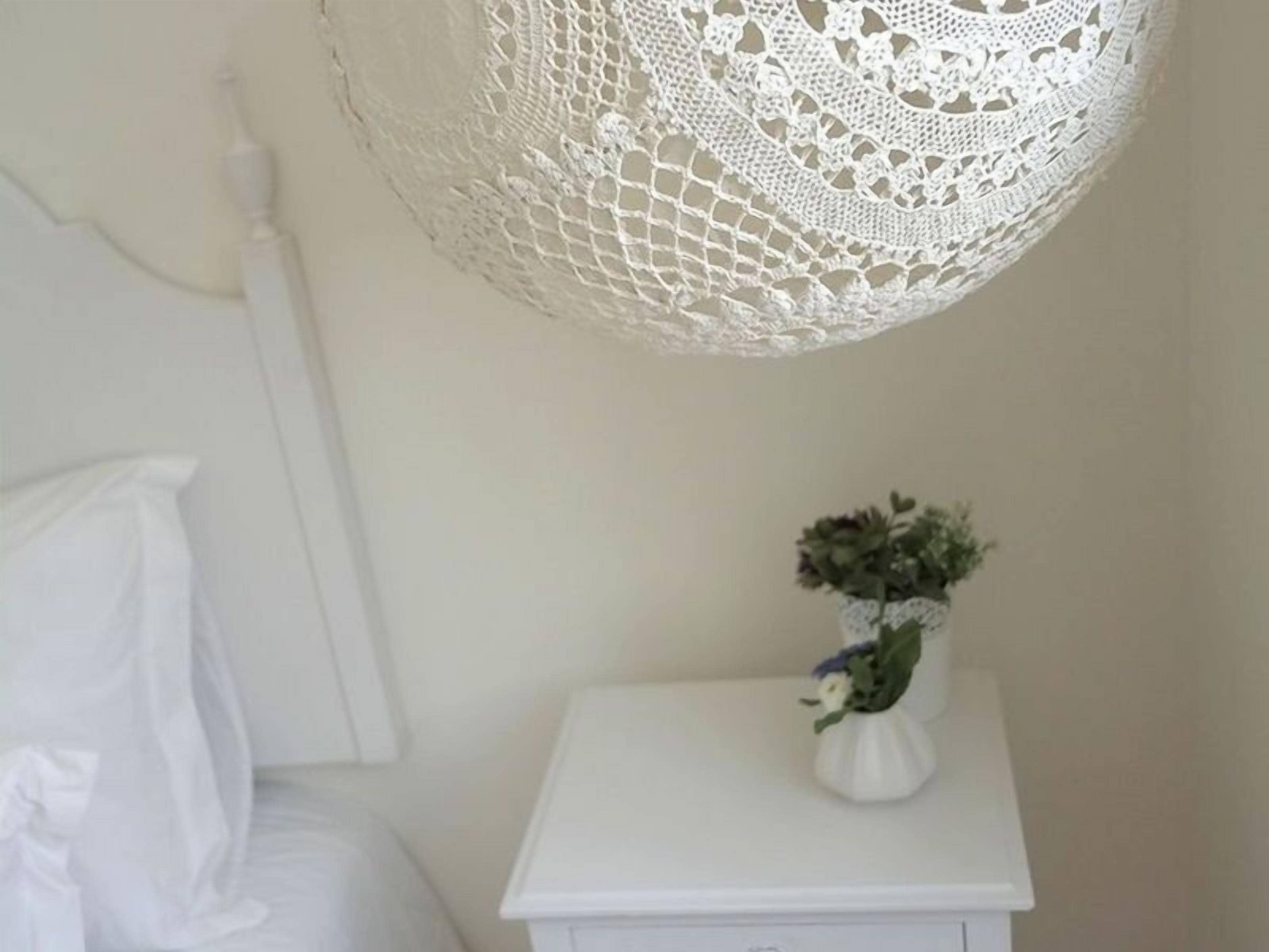 A white bedside table with a small white vase containing a plant.