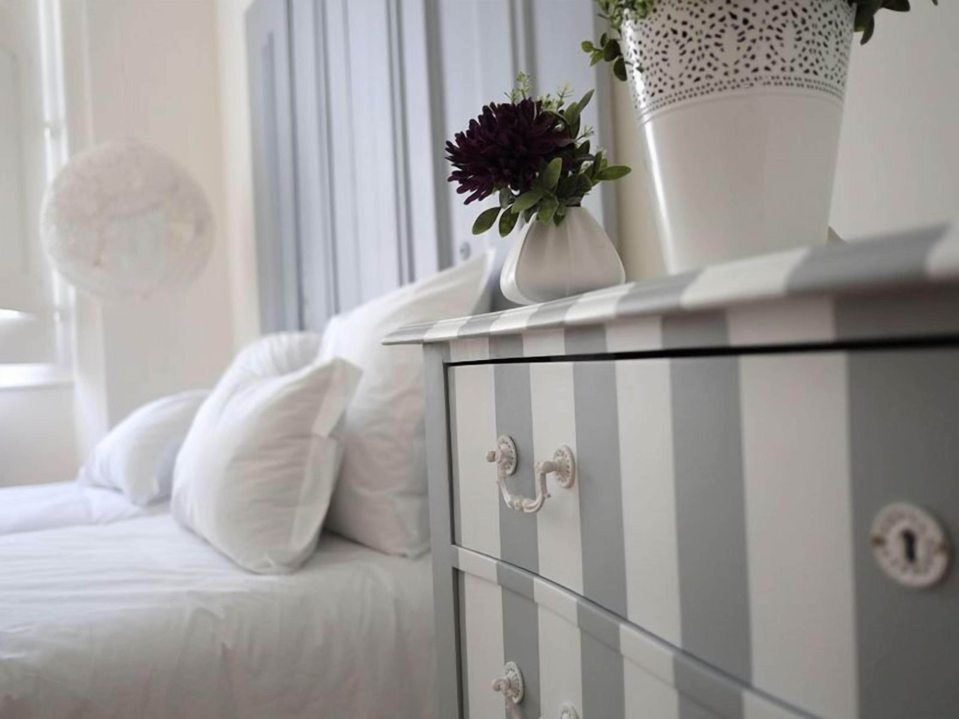 Een bed met witte beddengoed en een witte decoratieve object op het nachtkastje.