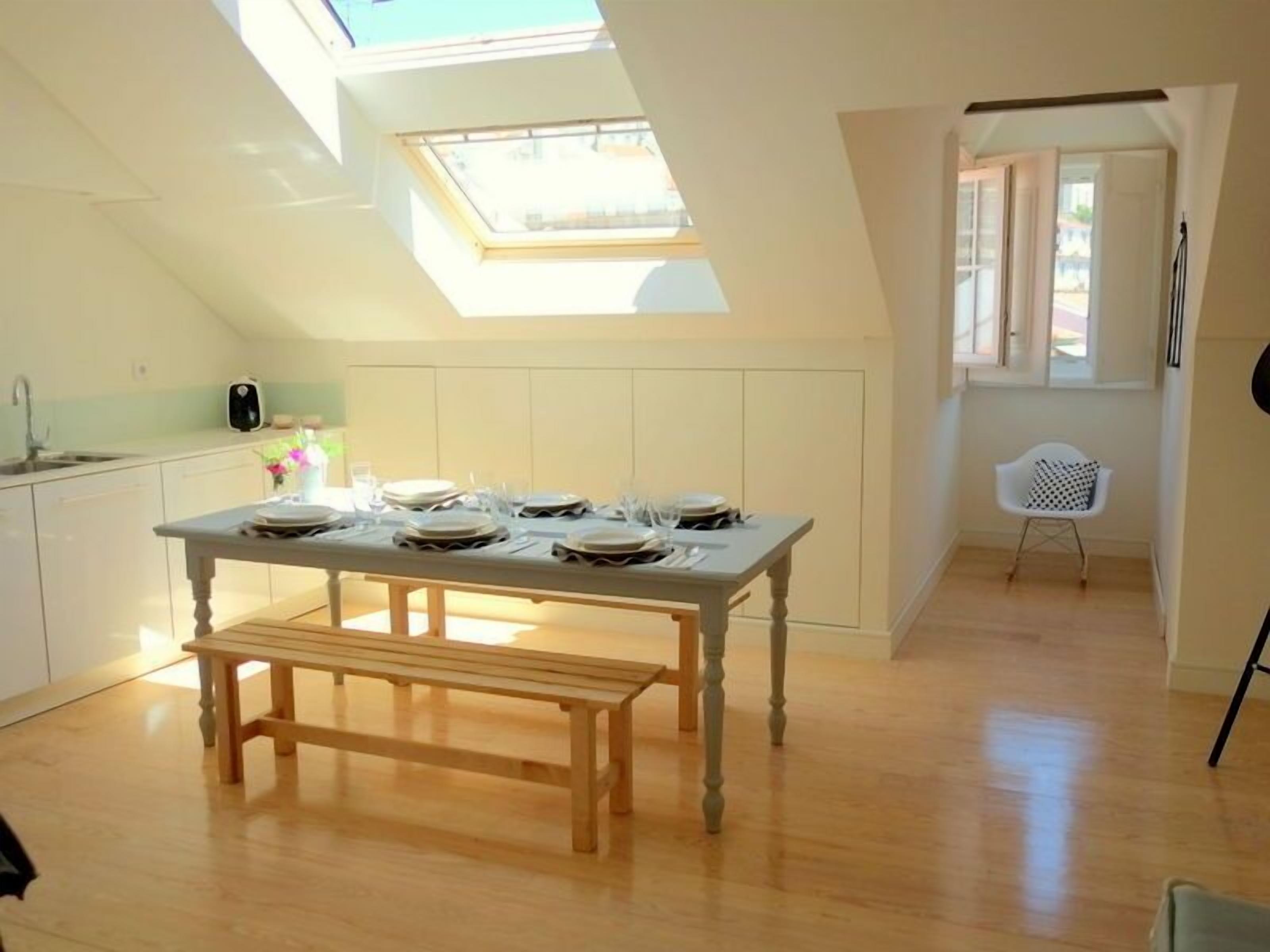 A dining area with a table set for four, a bench, and a skylight above.