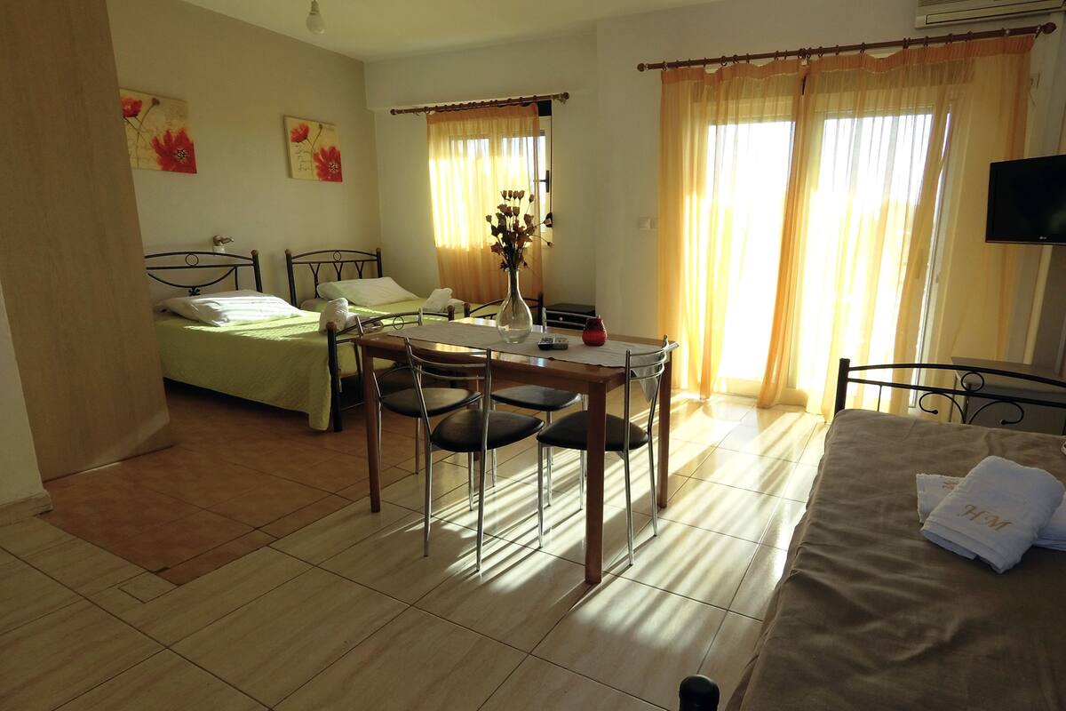 Una habitación de hotel con una cama, una mesa de comedor con sillas, un televisor y un sofá.