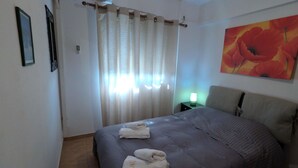 Ein Hotelzimmer mit Bett, Nachttisch, einem Bild und einem Fenster mit Vorhängen.