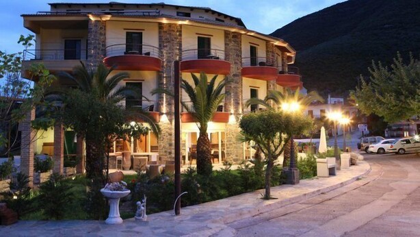 A multi-story hotel with balconies, outdoor seating, and a landscaped garden. - Delfini Hotel (Amfilochia)