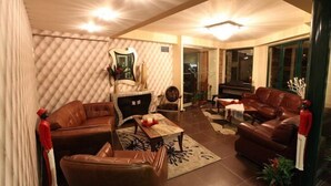 A living room with leather sofas, a coffee table, and a fireplace. - Delfini Hotel (Amfilochia)