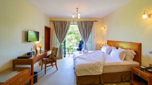 A hotel room with a bed, desk, chair, TV, and a balcony with curtains. - Lotos Inn & Suites, Nairobi (Nairobi)