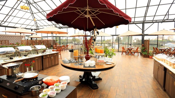 A spacious dining area with a high ceiling, large windows, and multiple dining tables. - Lotos Inn & Suites, Nairobi (Nairobi)