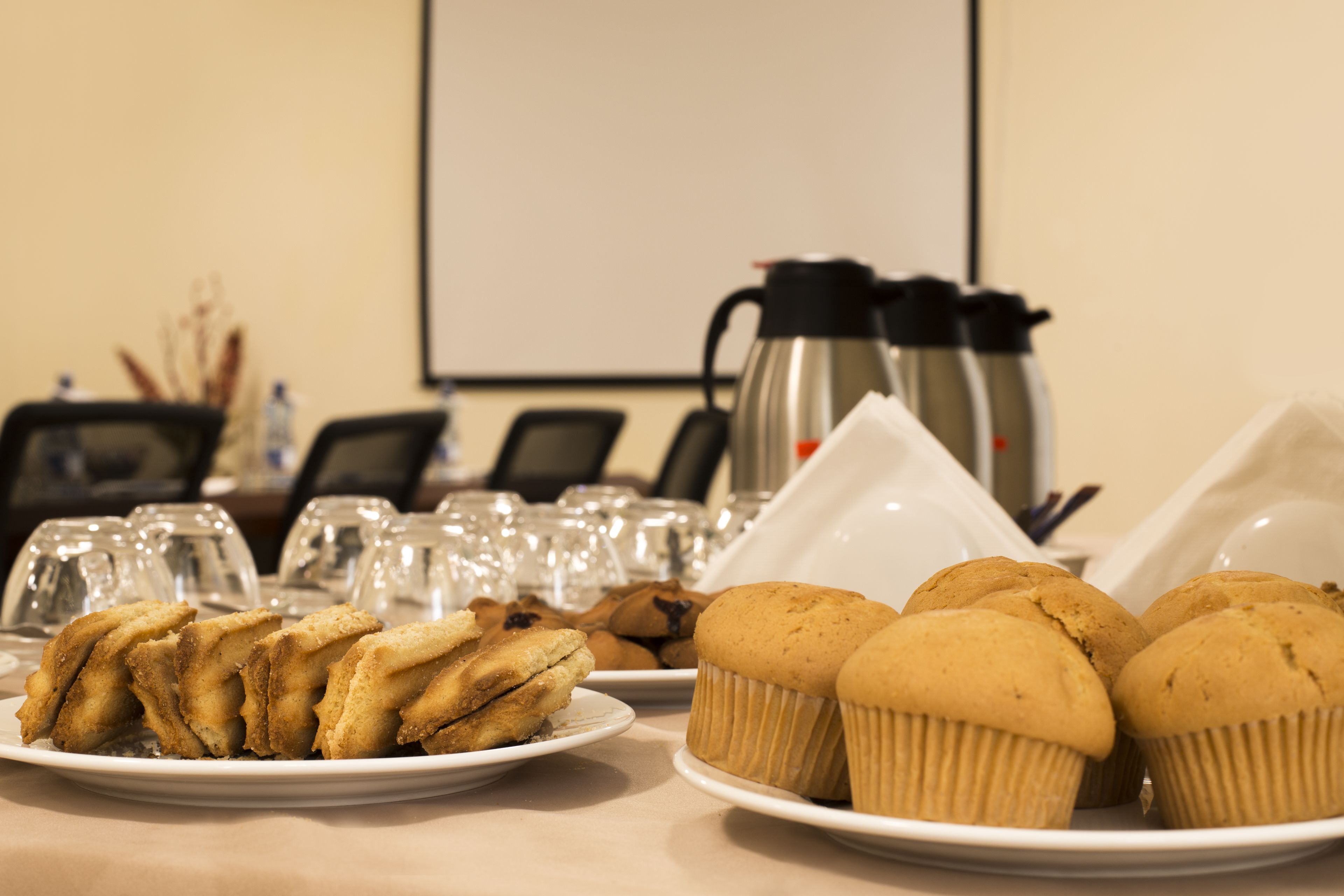 Una mesa con platos de pasteles y una cafetera.
