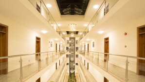 A multi-level hotel lobby with a central atrium, glass railings, and a chandelier. - Lotos Inn & Suites, Nairobi (Nairobi)