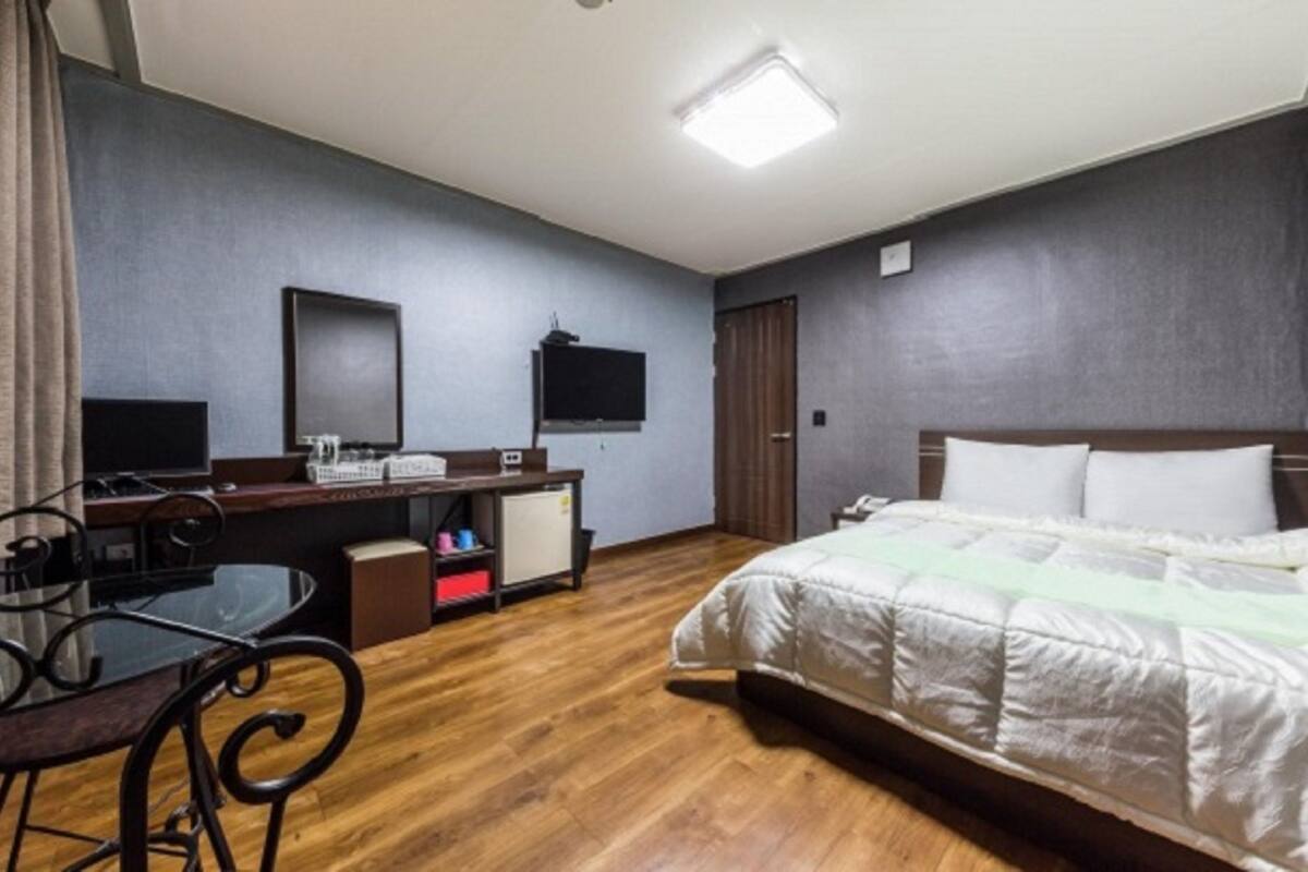 Una habitación de hotel con cama, escritorio, silla y televisor.