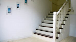 A staircase with white railings and wooden steps, leading to an upper floor.