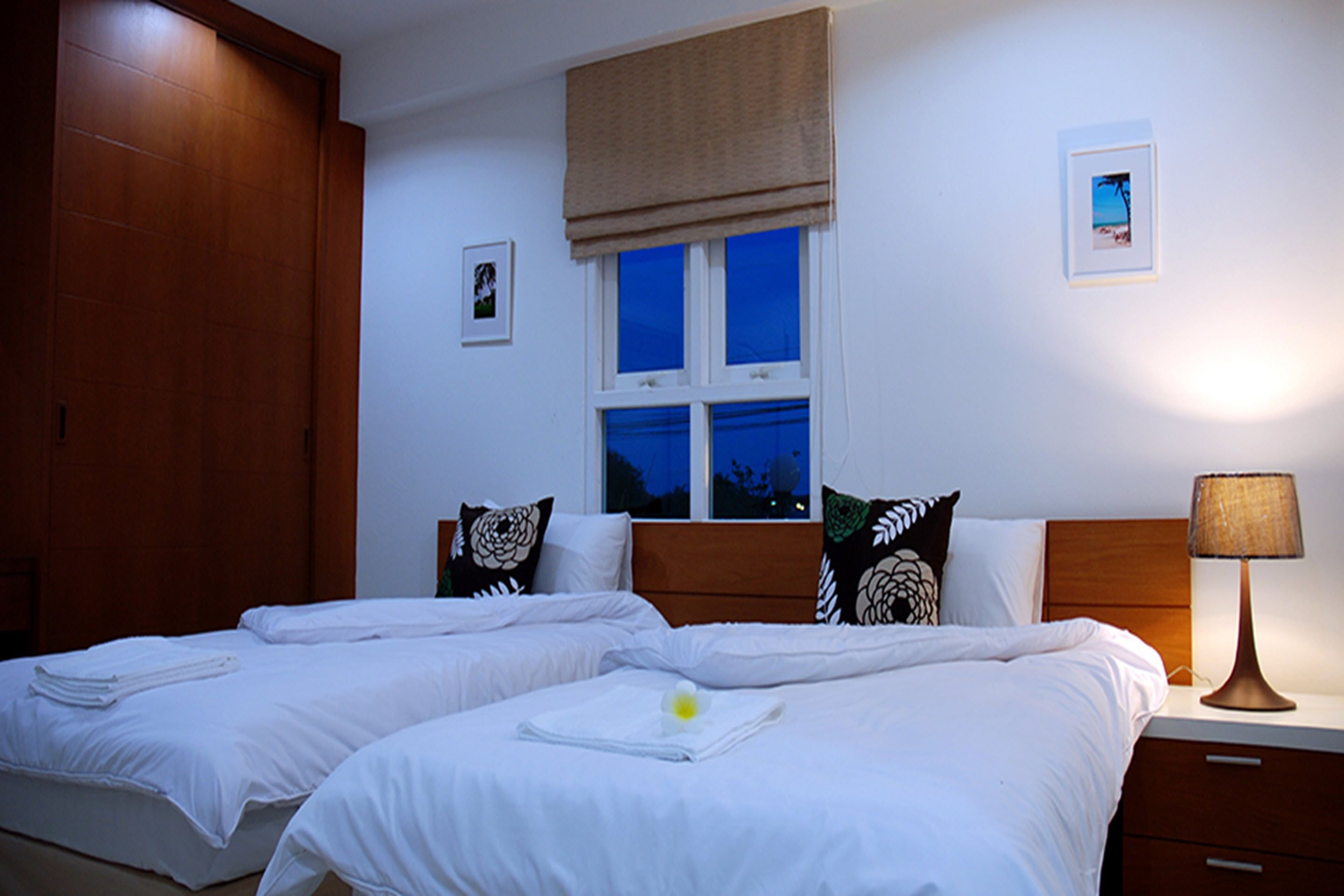 Une chambre d’hôtel avec deux lits, une fenêtre donnant sur un beau paysage, une armoire en bois et une table de chevet avec une lampe.