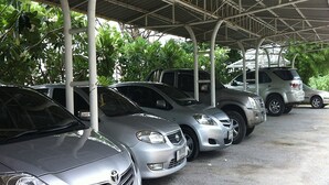 A covered parking area with several cars parked under a metal roof.