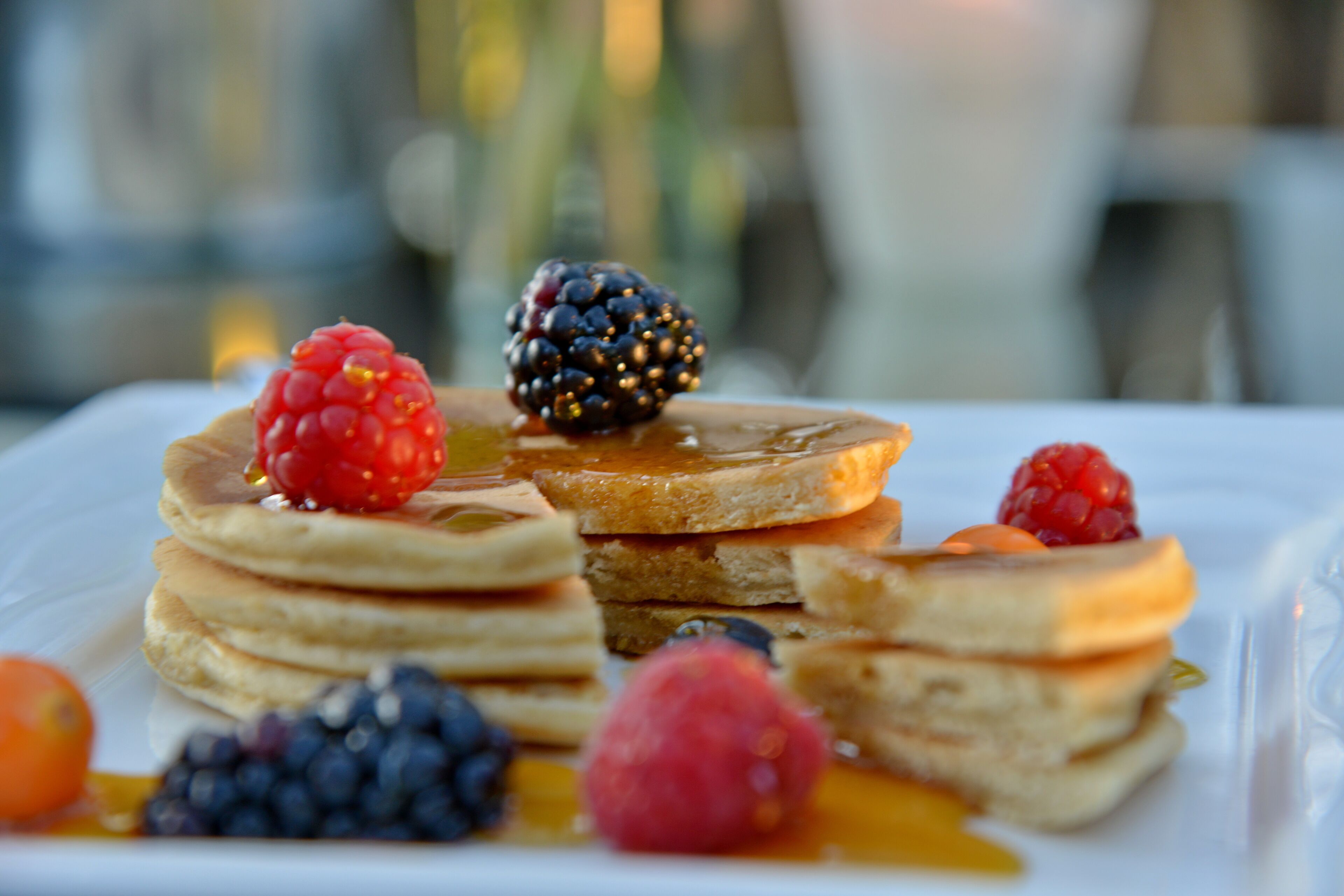 Una pila de tortitas con frutos rojos y jarabe.