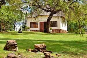 Una casa con recepción, rodeada de césped cuidado y rocas grandes.