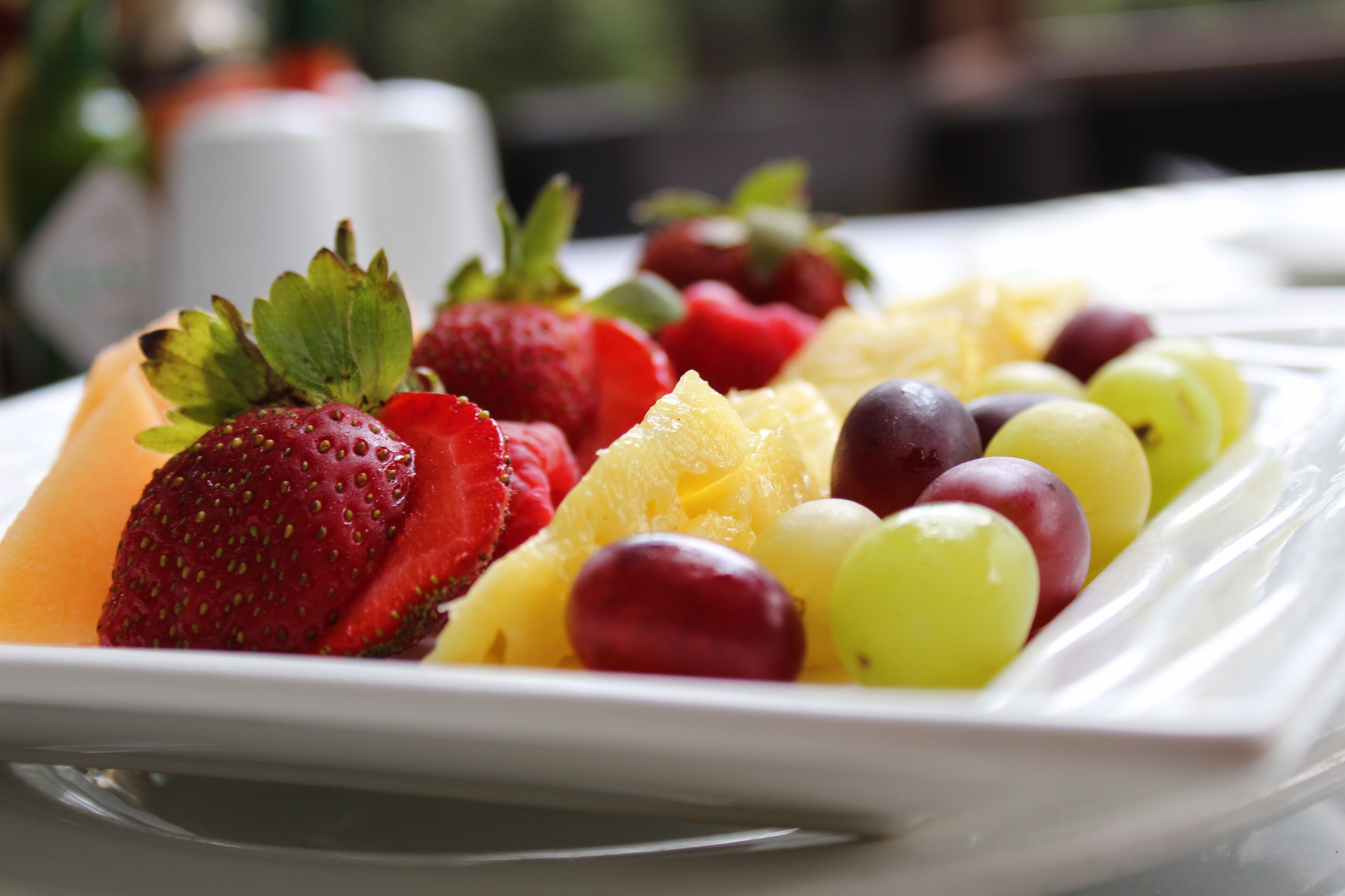 Une assiette de fruits variés, notamment des fraises, des raisins et de l’ananas.