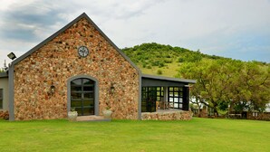 A stone building with a large arched entrance and a modern extension with large windows. - Thanda Manzi Country Hotel (Centurion)