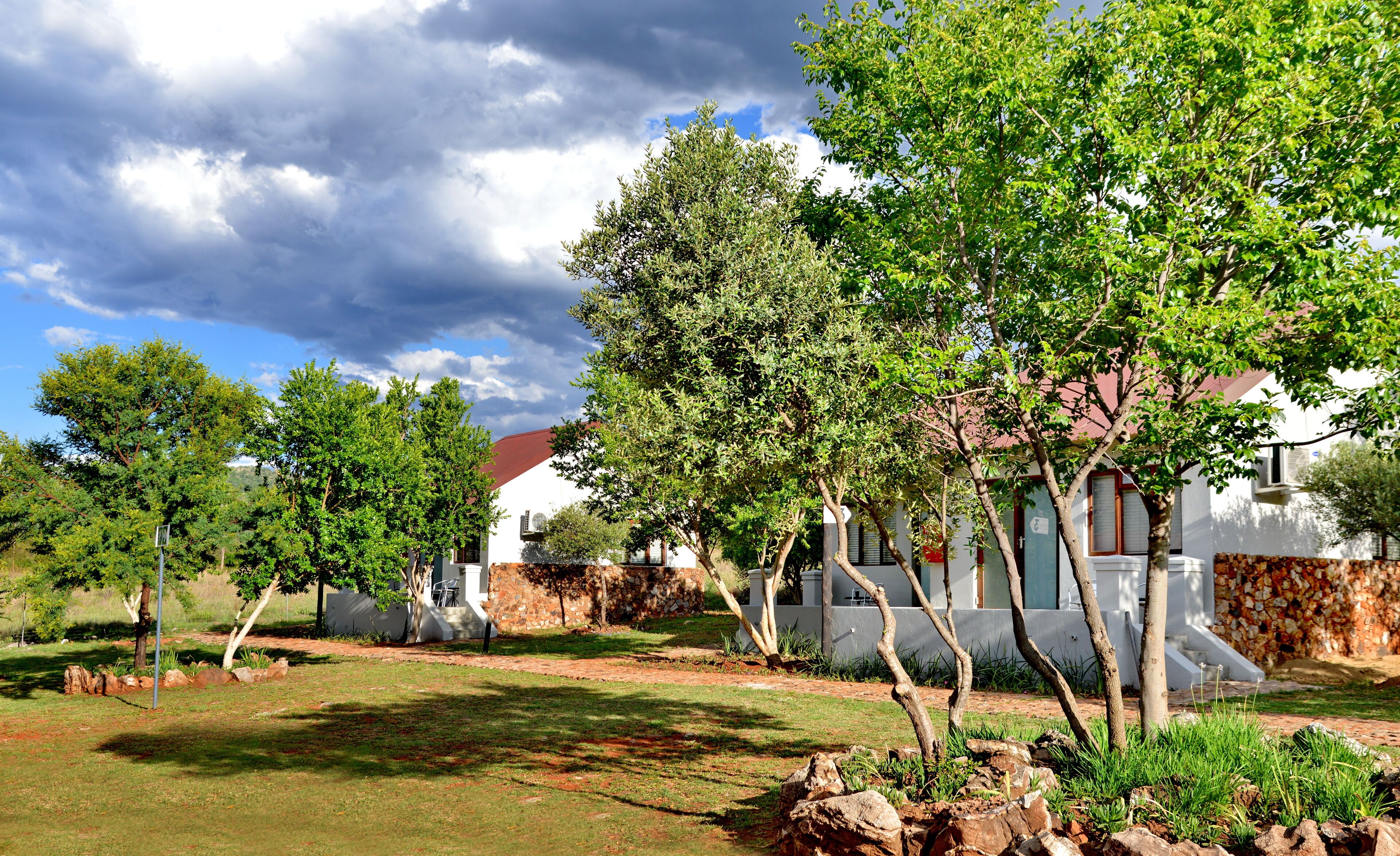 A residential area with a white house, a stone wall, and a grassy lawn.