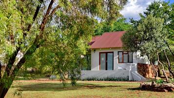 Set amidst a serene natural setting, this charming building features a front entrance with a glass door and a small set of steps.