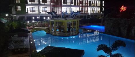 Una piscina al aire libre, sombrillas, sillones reclinables de piscina