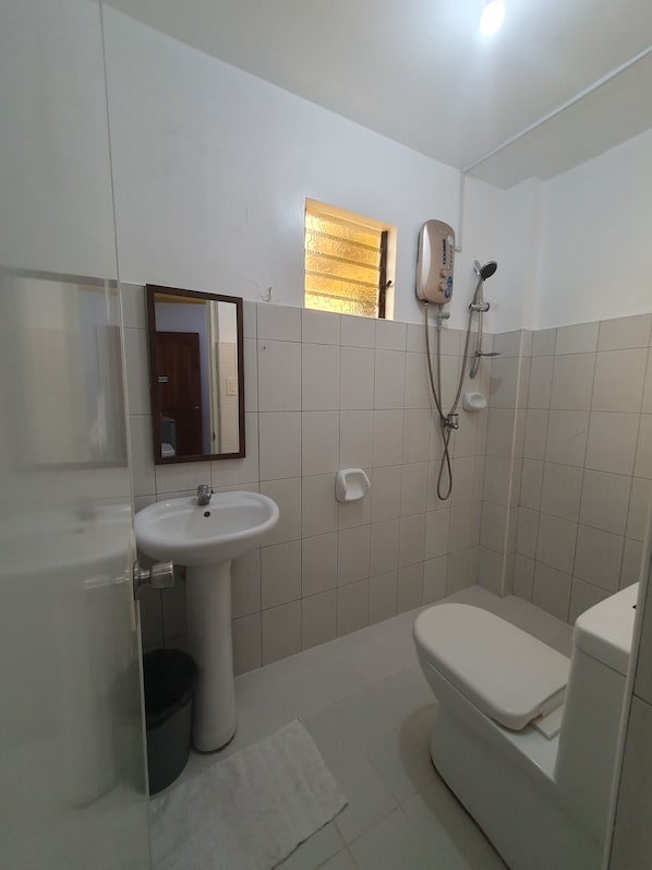 A bathroom with a toilet, sink, and shower.