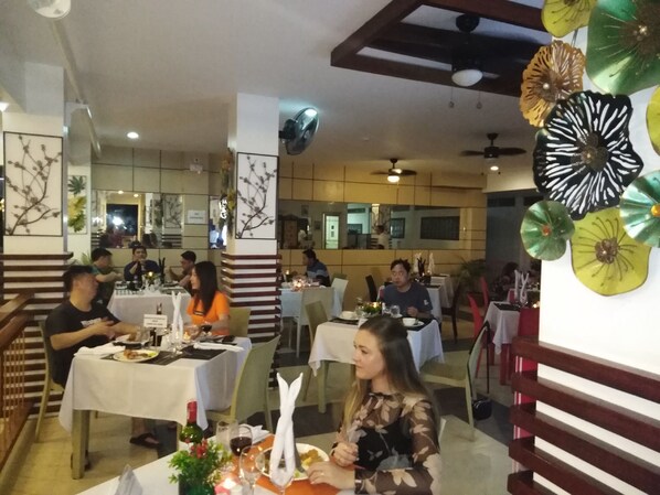 A restaurant with multiple tables, some with diners. There are decorative umbrellas on the wall. - Moalboal Tropics (Moalboal)