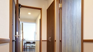 Un pasillo con suelo de madera, un área de comedor con sillas y una puerta cerrada con marco de madera.