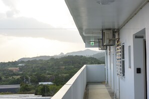 A balcony with a view of a mountainous landscape, a white building with a door and window, and a green directional sign. - Condominium Resort Nago Grand Sedona (Nago)