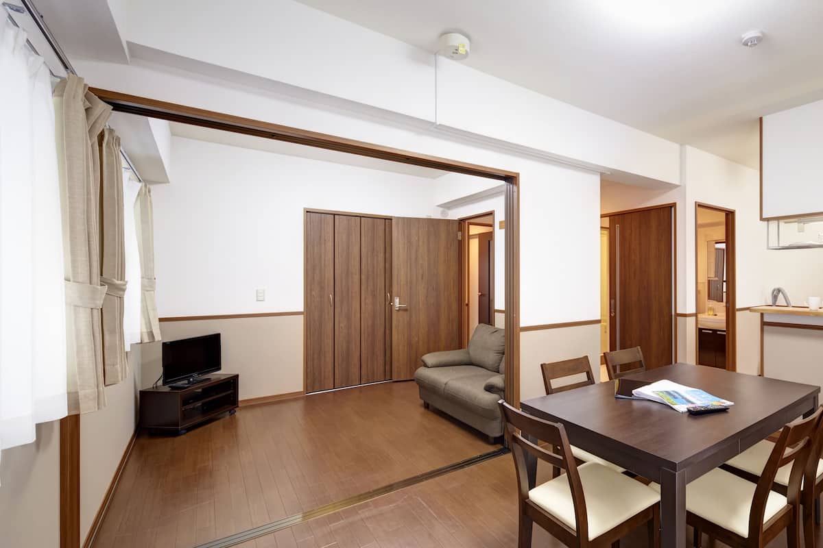 A modern living room with a sofa, TV, and dining table.