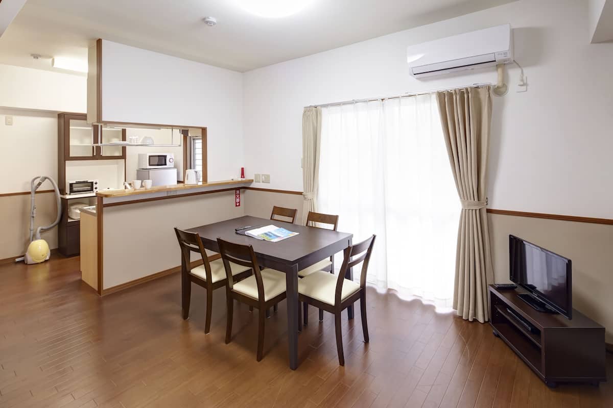 A compact living space with a dining table, chairs, a TV, and a kitchenette.
