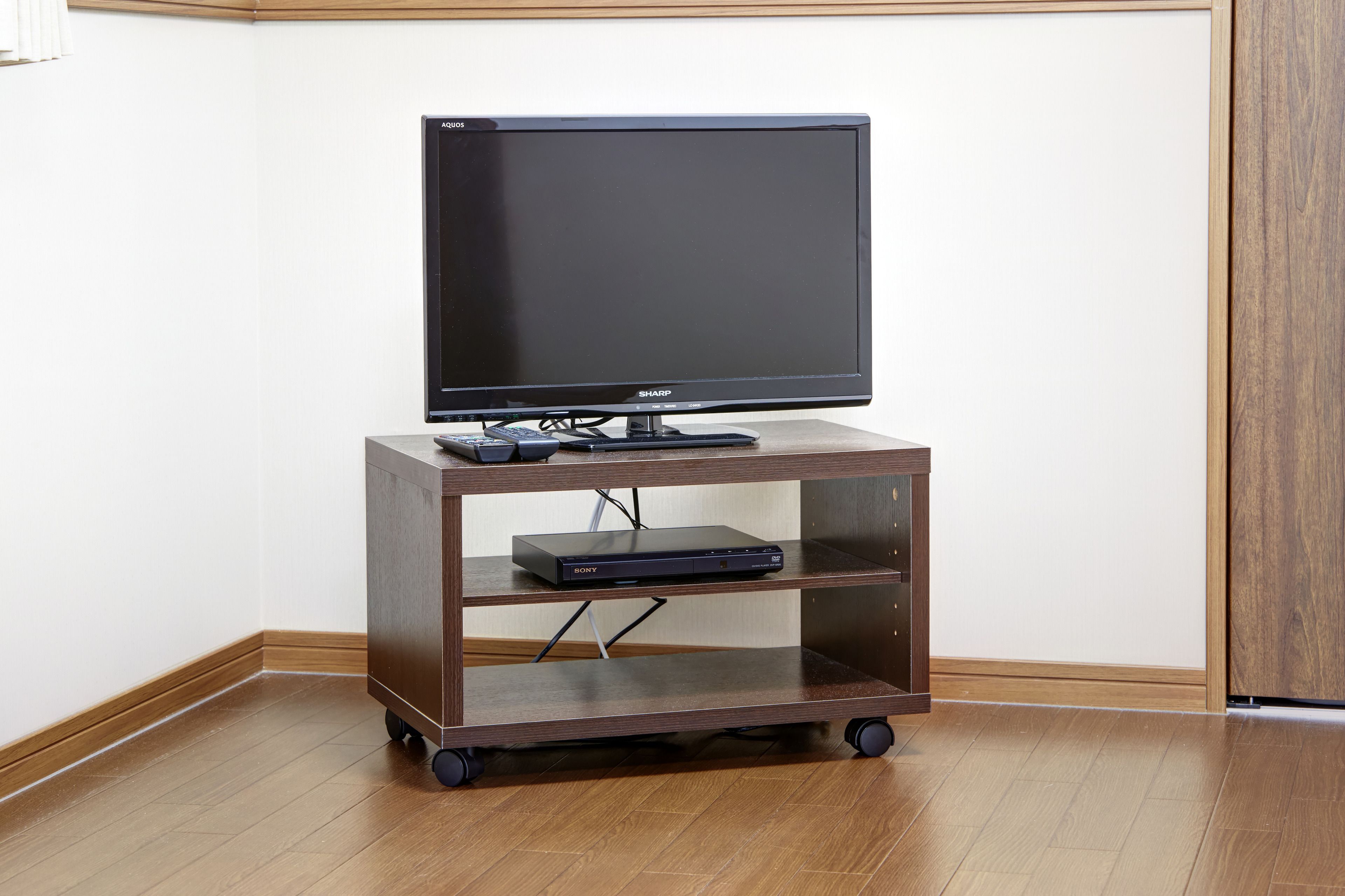 A wooden TV stand with a flat-screen TV and a Blu-ray player.