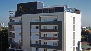 Ein mehrstöckiges Hotel mit Balkonen, einem gut sichtbaren Kronenlogo und dem Schriftzug 'Queens Hotel' an der Fassade.