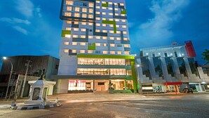 Un hôtel à plusieurs étages, doté d’un design moderne, avec une entrée imposante, des portes en verre et un auvent vert.