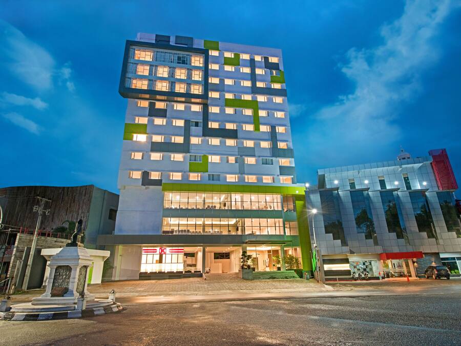 Un hôtel à plusieurs étages, doté d’un design moderne, avec une entrée imposante, des portes en verre et un auvent vert.