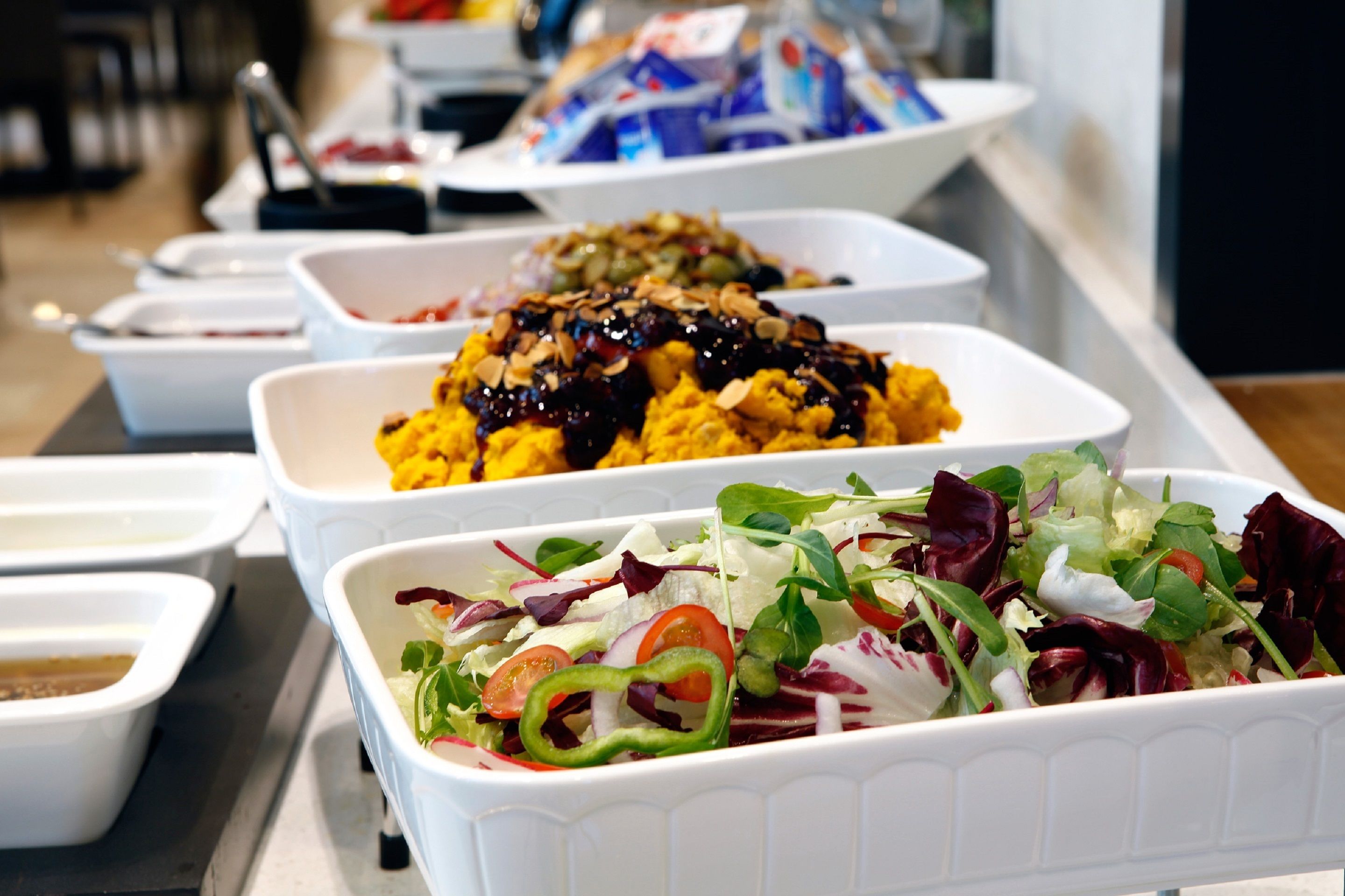 A buffet with various dishes including a salad, a fruit salad, and a dish with nuts and sauce.