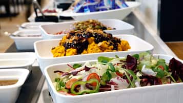 A buffet with various dishes including a salad, a fruit salad, and a dish with nuts and sauce.