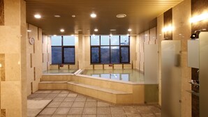 A modern indoor swimming pool with clear windows, a wooden ceiling, and a tiled floor.