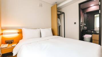 A hotel room with a bed, bedside lamp, phone, and a mirror.