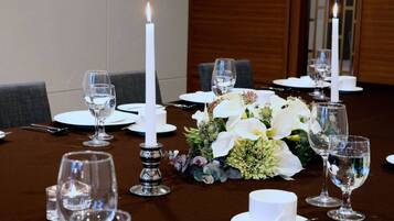 A dining table set with white plates, glasses, and a centerpiece of white flowers.