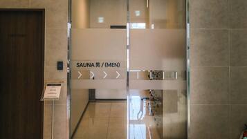 A modern entrance to a sauna facility with a clear sign indicating it is for men.