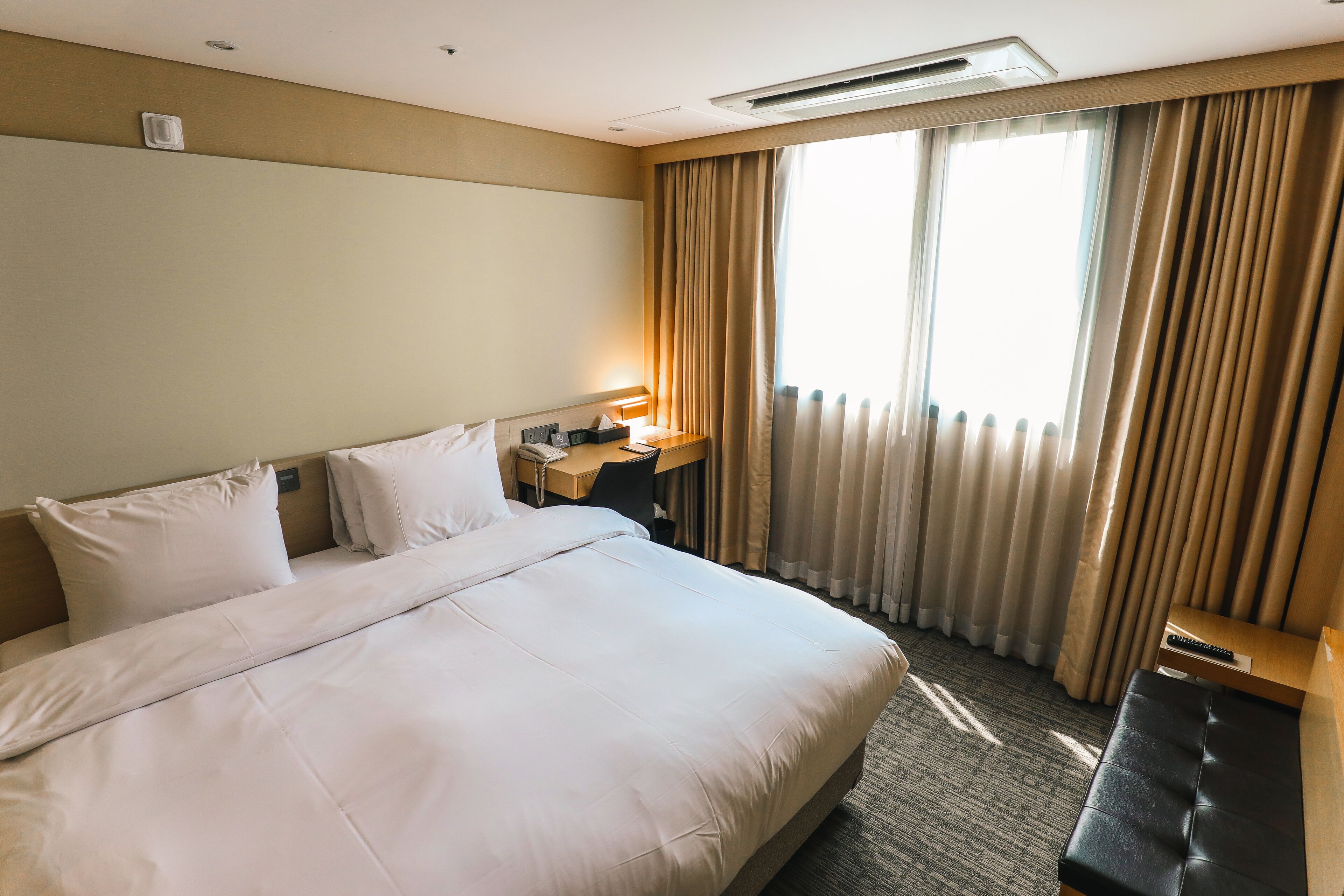 Un cuarto de hotel con una cama grande, un escritorio con lámpara y vistas al exterior a través de la ventana.