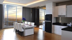 Een moderne keuken met witte kasten, een zwarte koelkast en een eethoek met een tafel en stoelen.