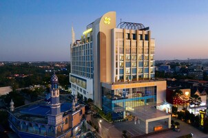 Un hotel moderno con una fachada de vidrio destacada, una torre con cúpula decorada y un letrero que indica hotel y centro de convenciones.
