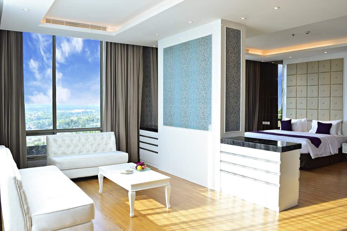 Una habitación de hotel moderna con un ventanal grande, un sofá, una mesita de centro, una cama con cabecero y una pequeña kitchenette.