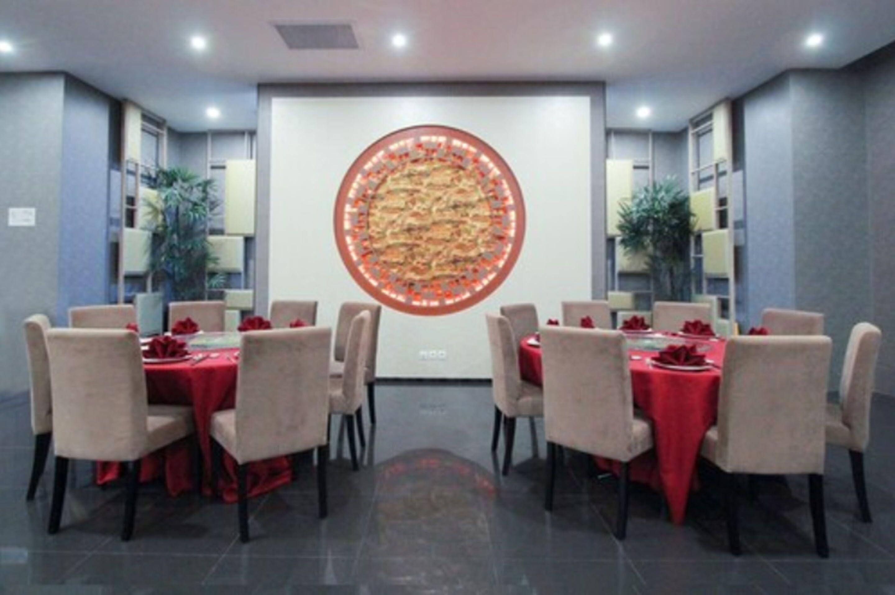 A conference room with round tables, red tablecloths, and beige chairs.