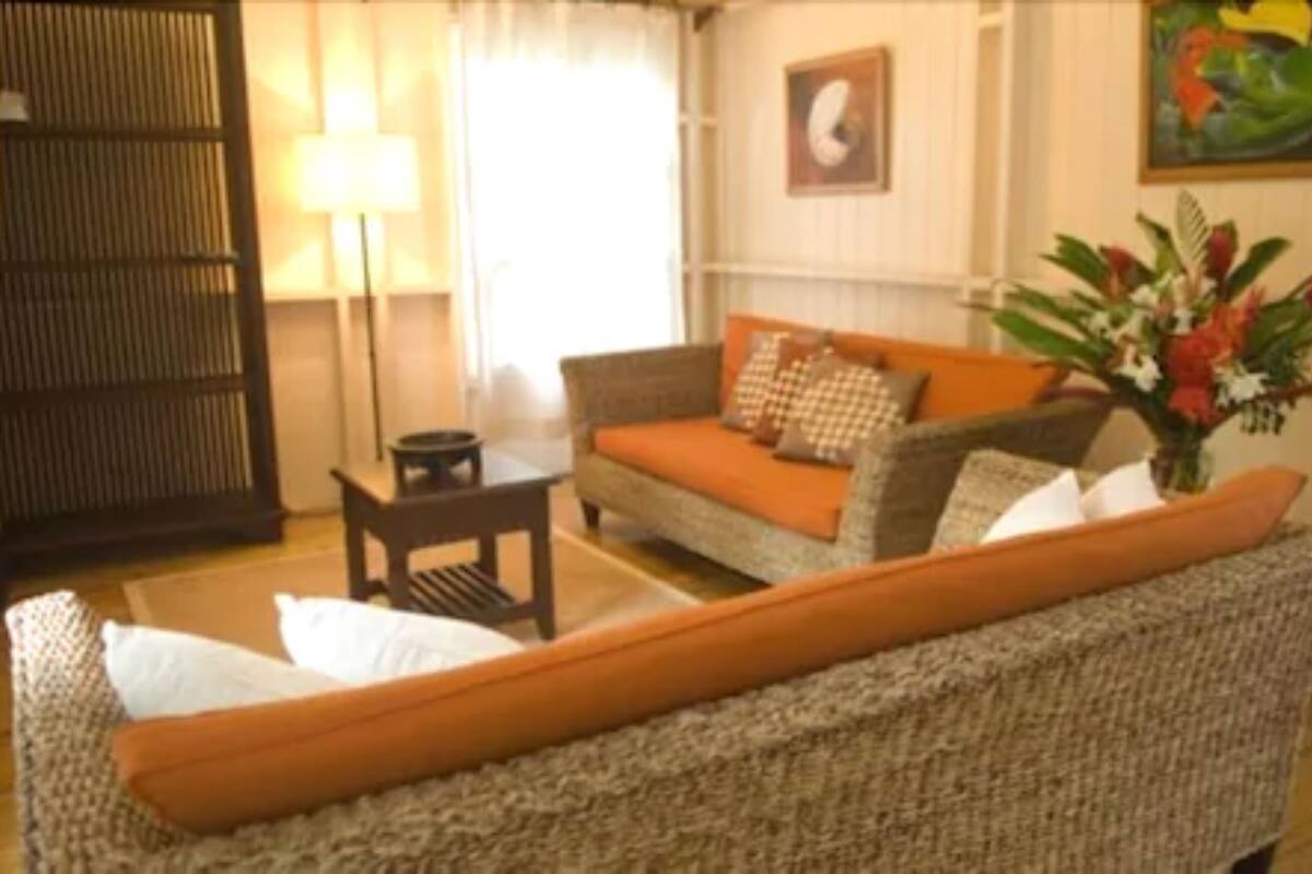 A living room with a sofa, a small table, a lamp, and a painting on the wall.
